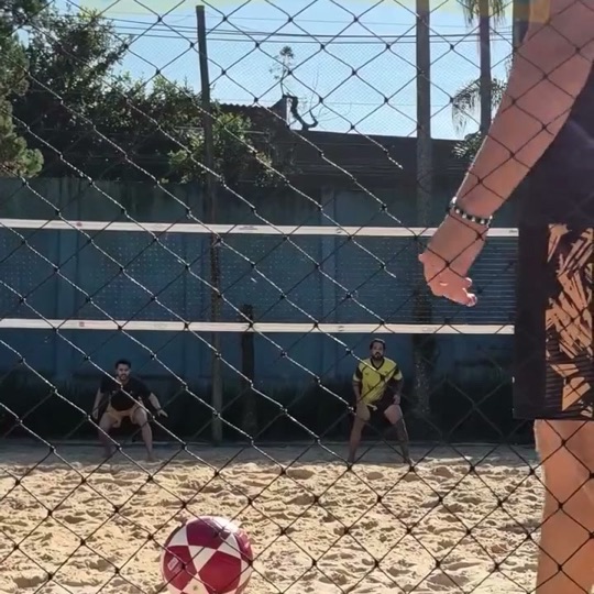 Bola de futevôlei na areia, vista pela rede
